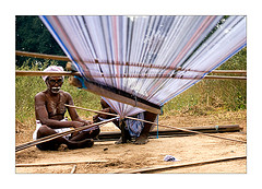 An Indian weaver prepares to make cloth on his loom.  Photo by Claude Renault at Fliker.com